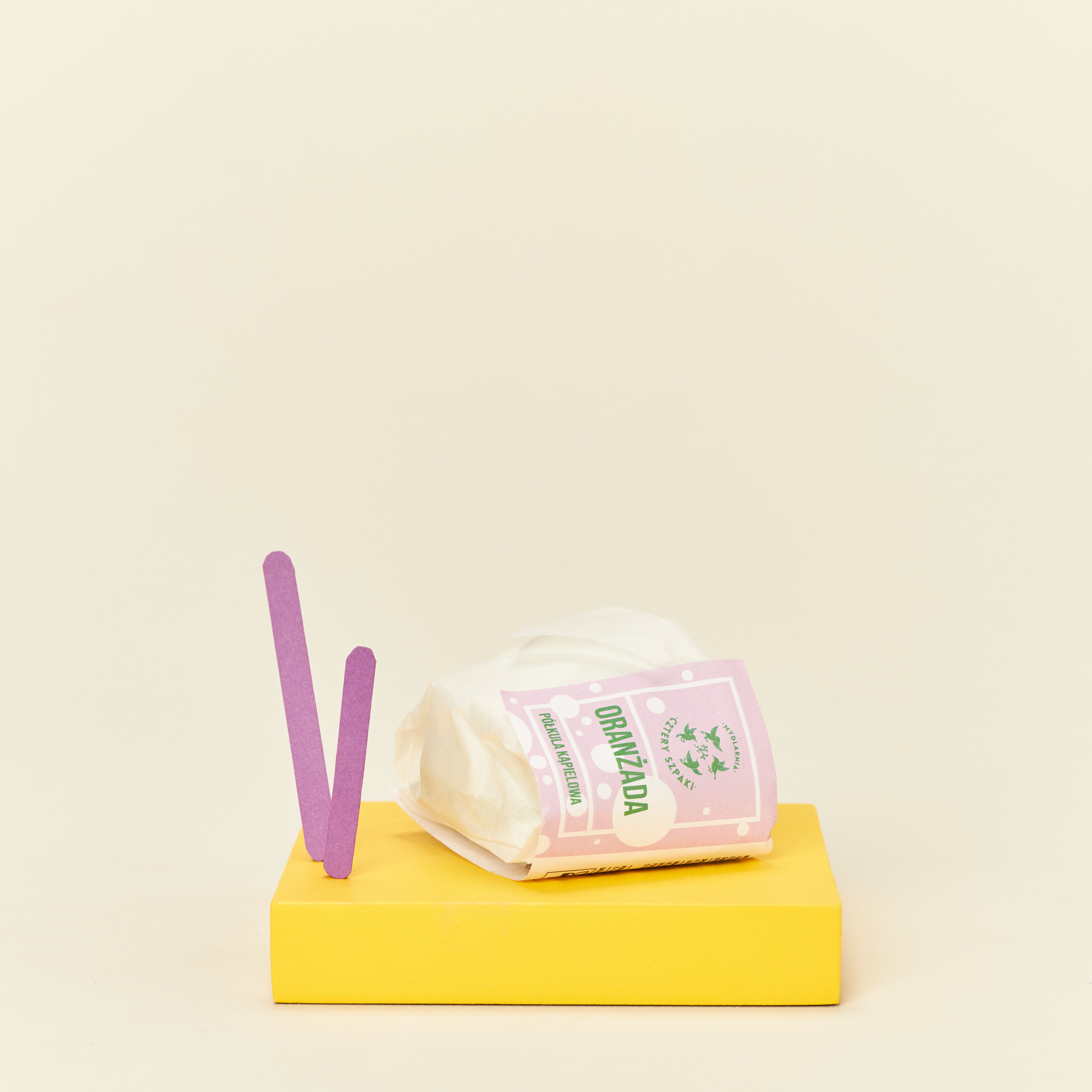 Półkula kąpielowa Oranżada w papierowym opakowaniu.