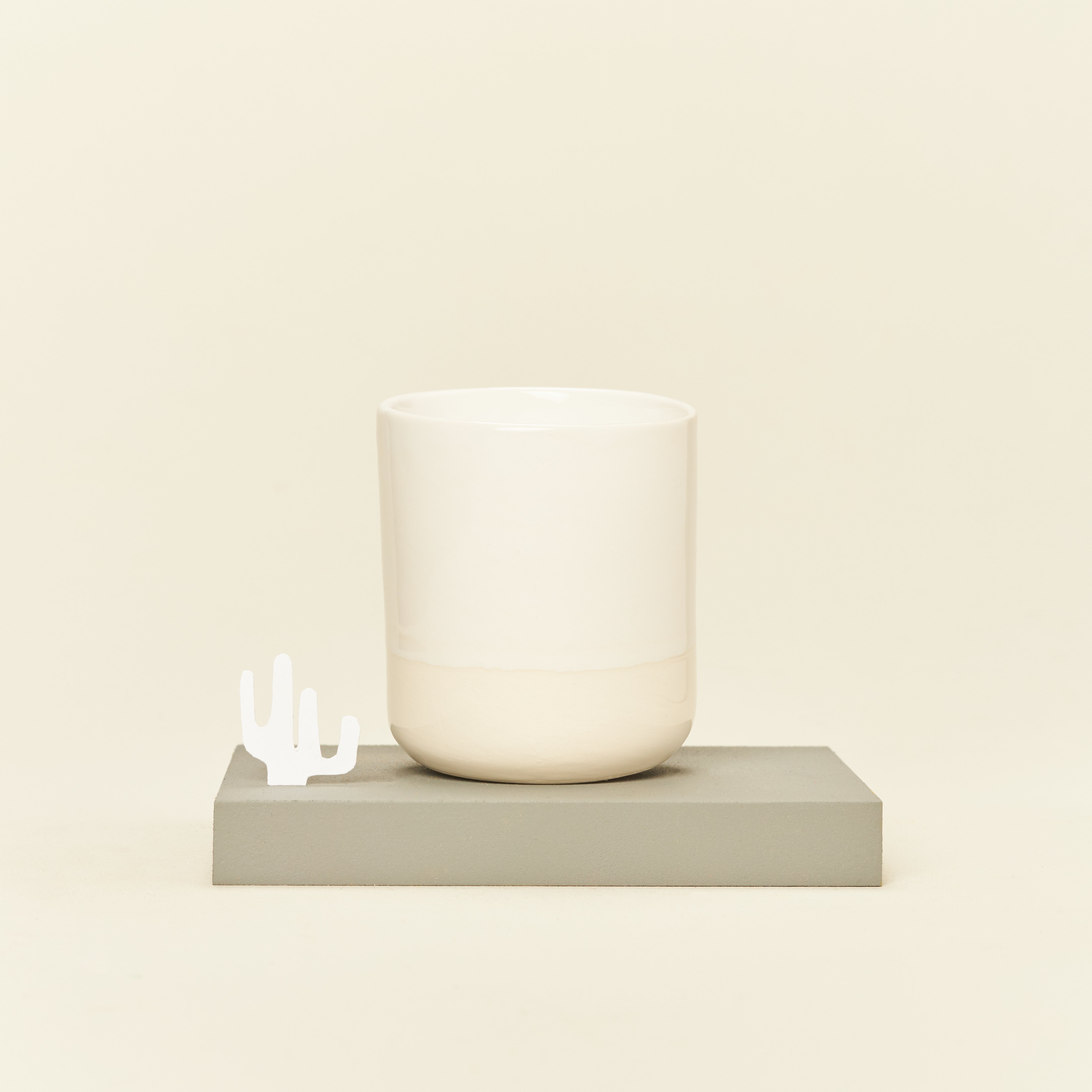 Ceramiczny kubek bez uszka w kolorze złamanej bieli.