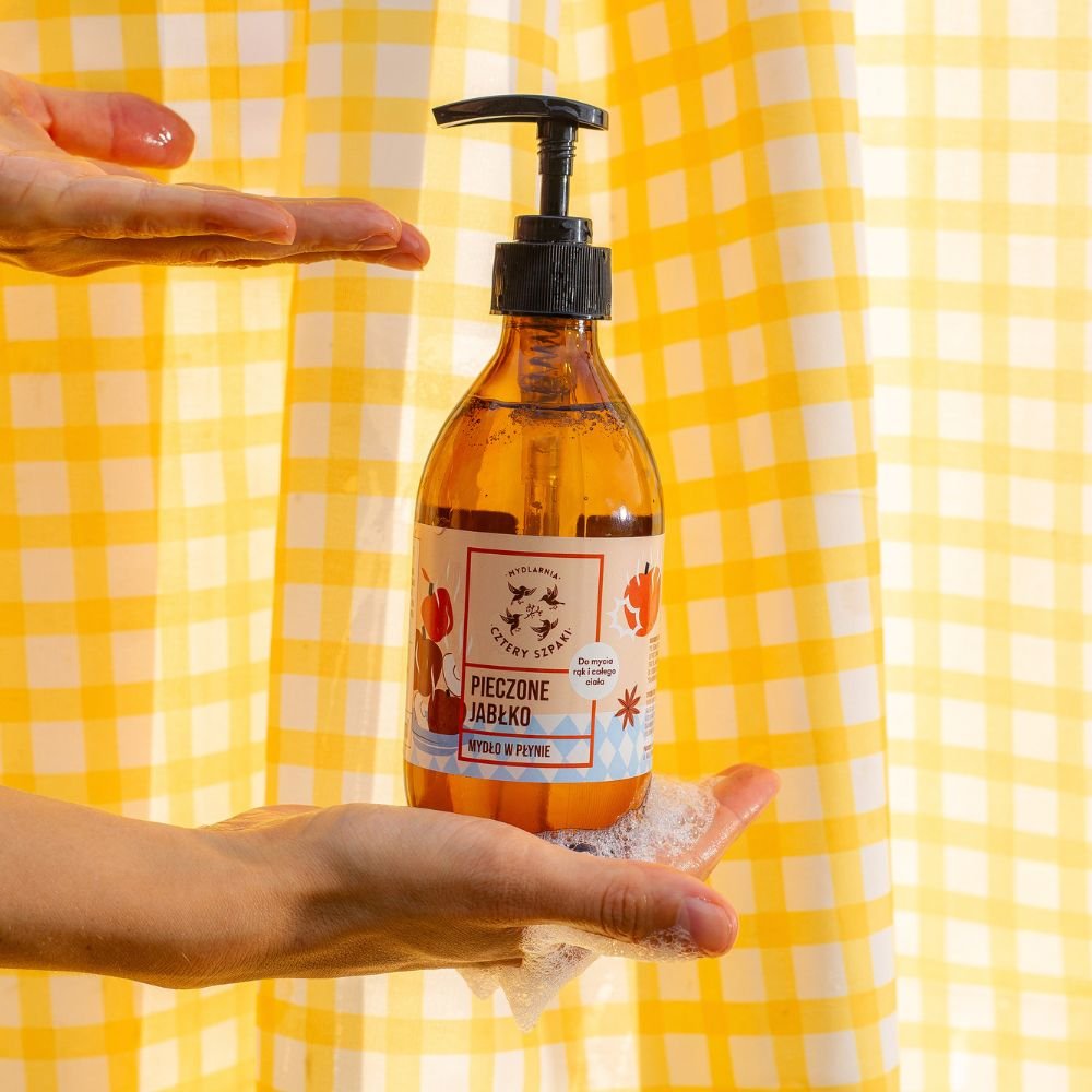 Zdjęcie mydła w płynie Pieczone Jabłko na tle ręcznika w żółto białą kratkę. 
