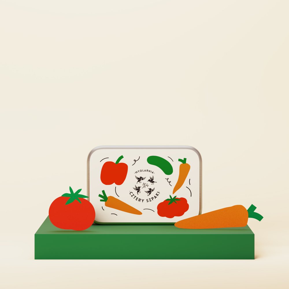 Prostokątna puszka z kolorowymi ilustracjami warzyw, w tym papryką, marchewką i pomidorem, stoi na zielonej platformie. Puszka posiada logo oraz napis „Mydlarnia Cztery Szpaki” na jasnym tle.